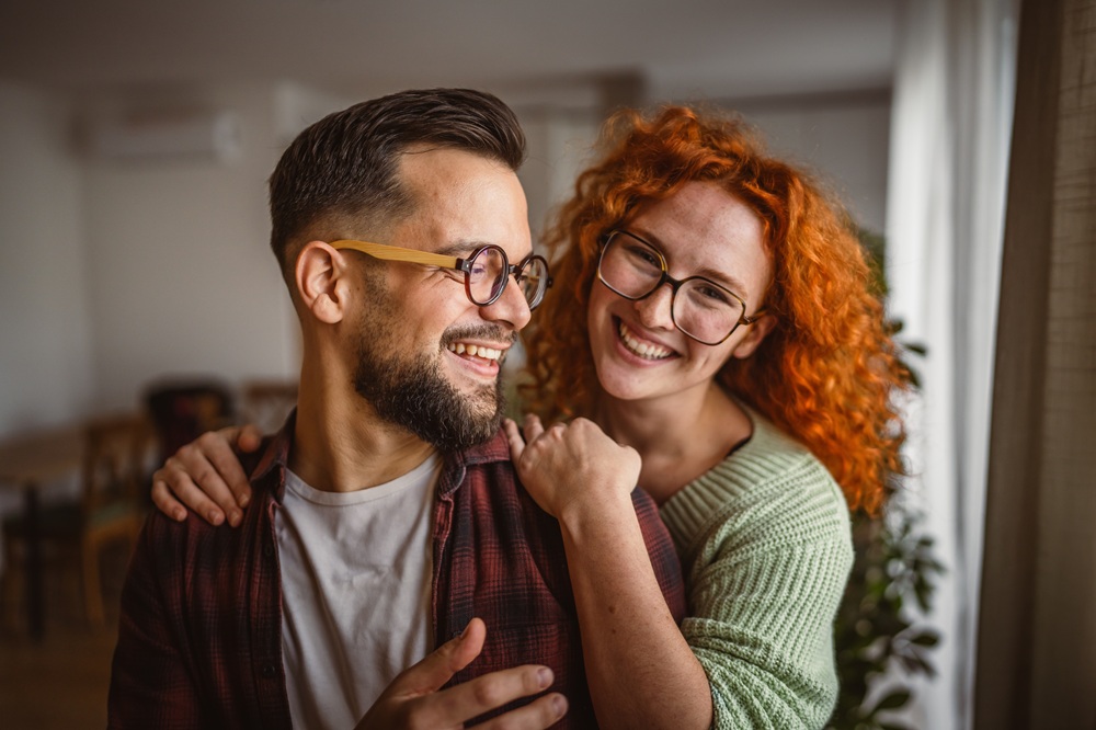 Smiling couple wearing glasses and embracing, representing improved vision and lifestyle after eye surgery – smile eye surgery mesa