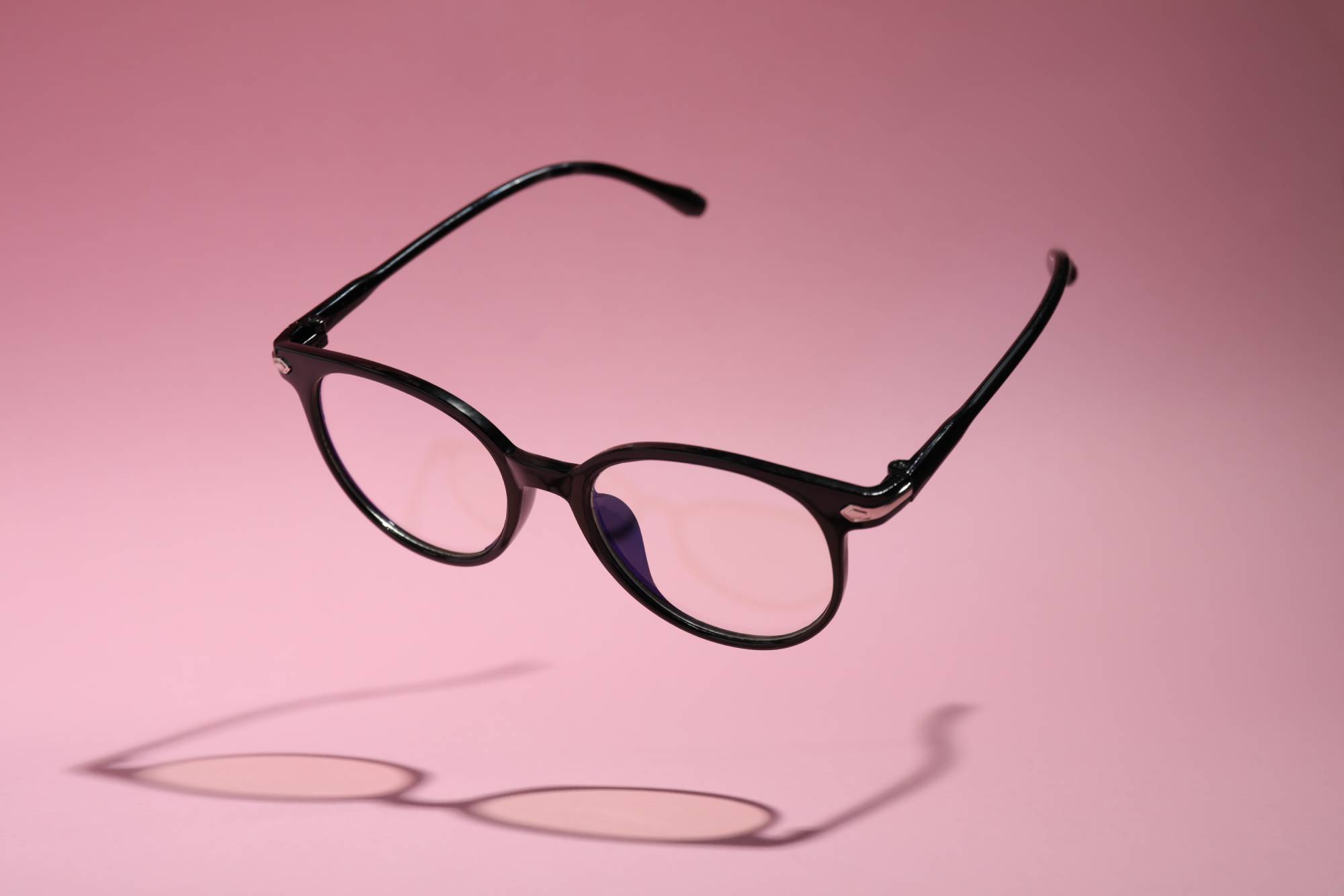 Stylish pair of glasses with black frame on pink background