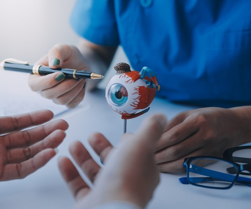 Eye care professional discussing vision correction with an eye model and patient during consultation for PRK – PRK