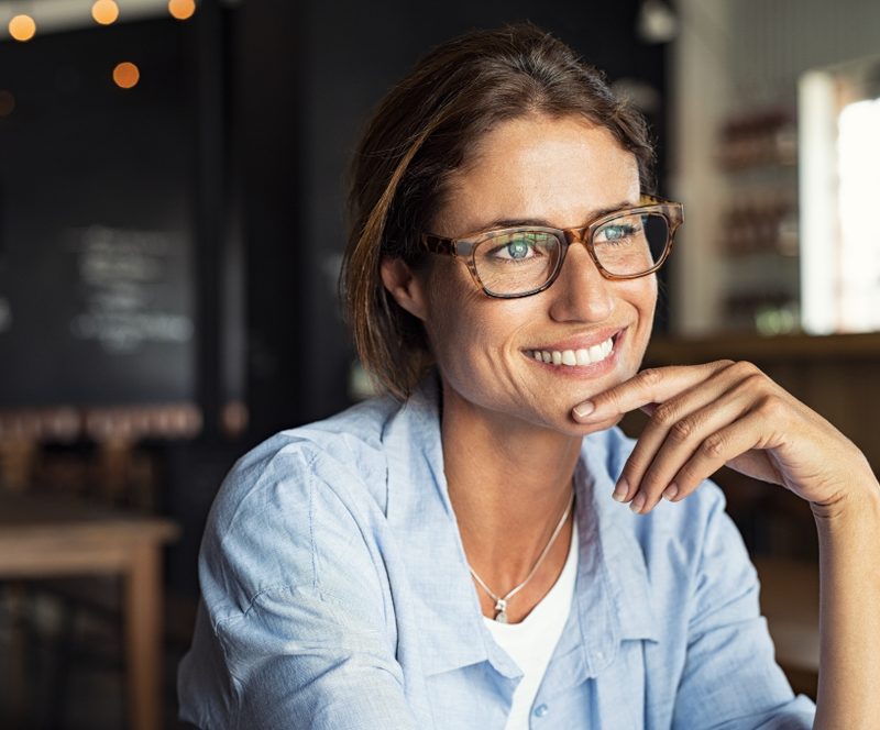 Woman wearing glasses smiling thoughtfully while learning about LASIK eye surgery outcomes and whether does lasik work – does lasik work