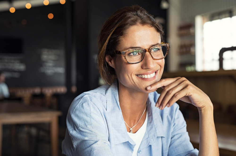Woman wearing glasses smiling thoughtfully while learning about LASIK eye surgery outcomes and whether does lasik work – does lasik work